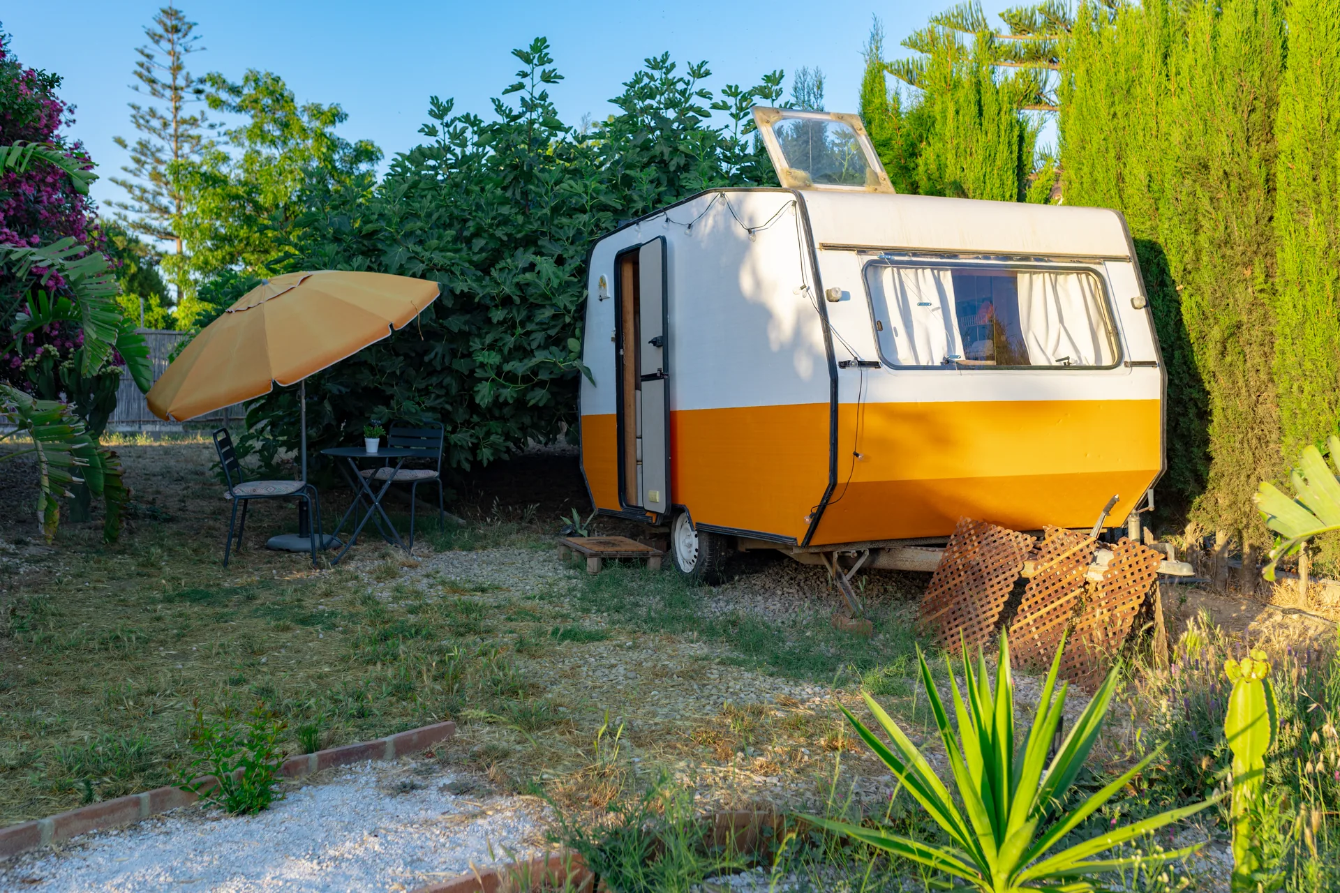 Orange Dreams — caravana naranja entre cipreses